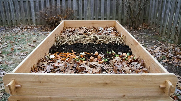 A Timberlane Gardens Select Cedar raised garden bed outdoors in late fall, filled with a natural mix of leaves, soil, and vegetable scraps for winter composting.